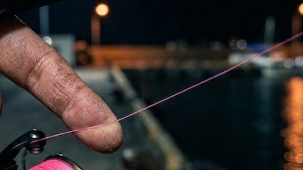 指でリールから出ているラインに触れている接写