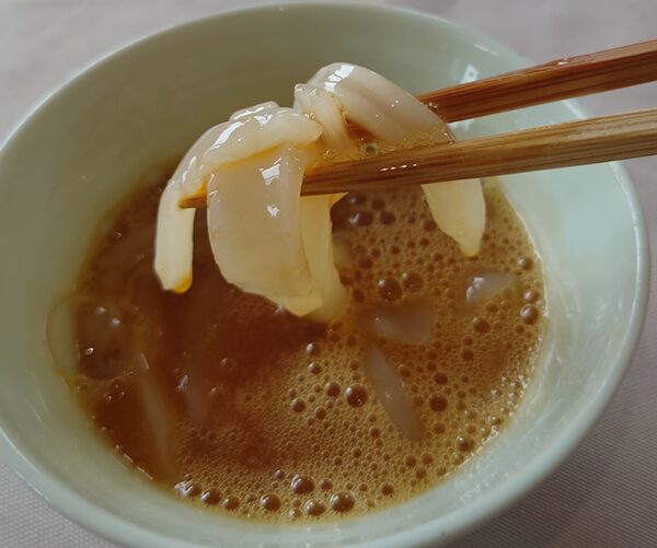 めんつゆ、卵黄にからめたアオリイカの刺身の写真