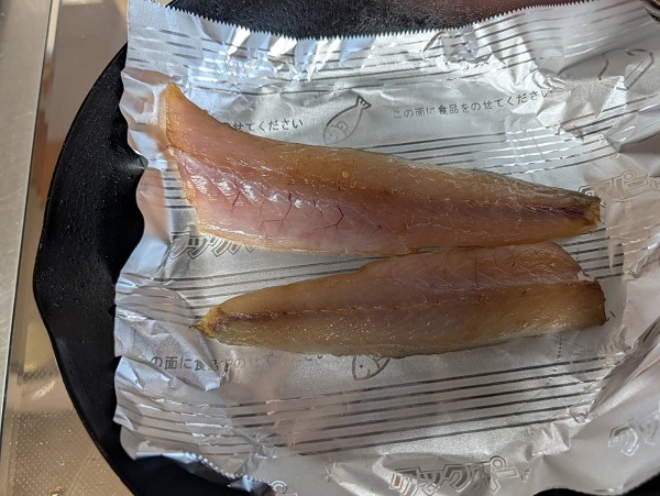フライパンの上でカマスを焼く。フライパンホイルも敷かれている。
